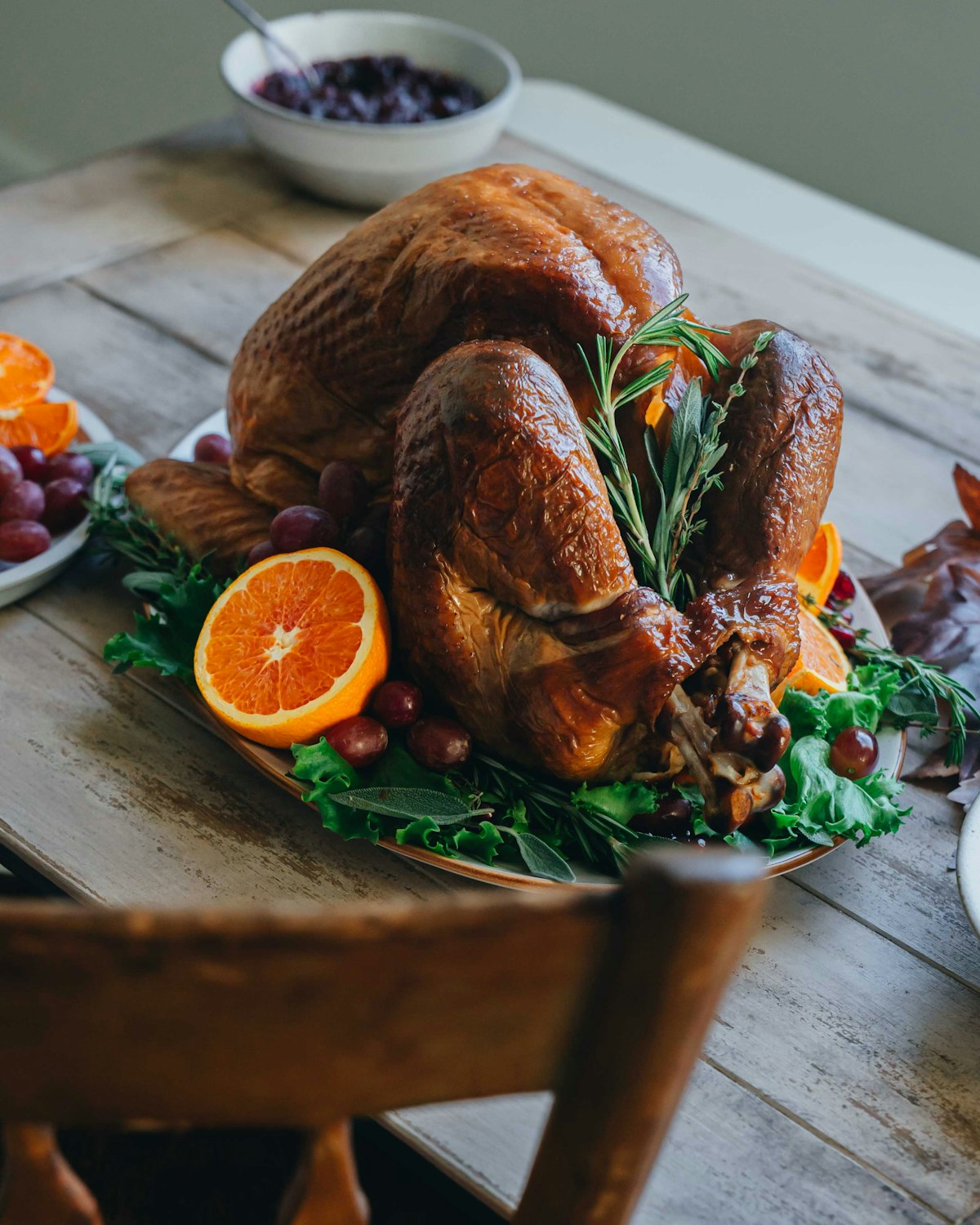 A golden roasted turkey on a platter with oranges and rosemary